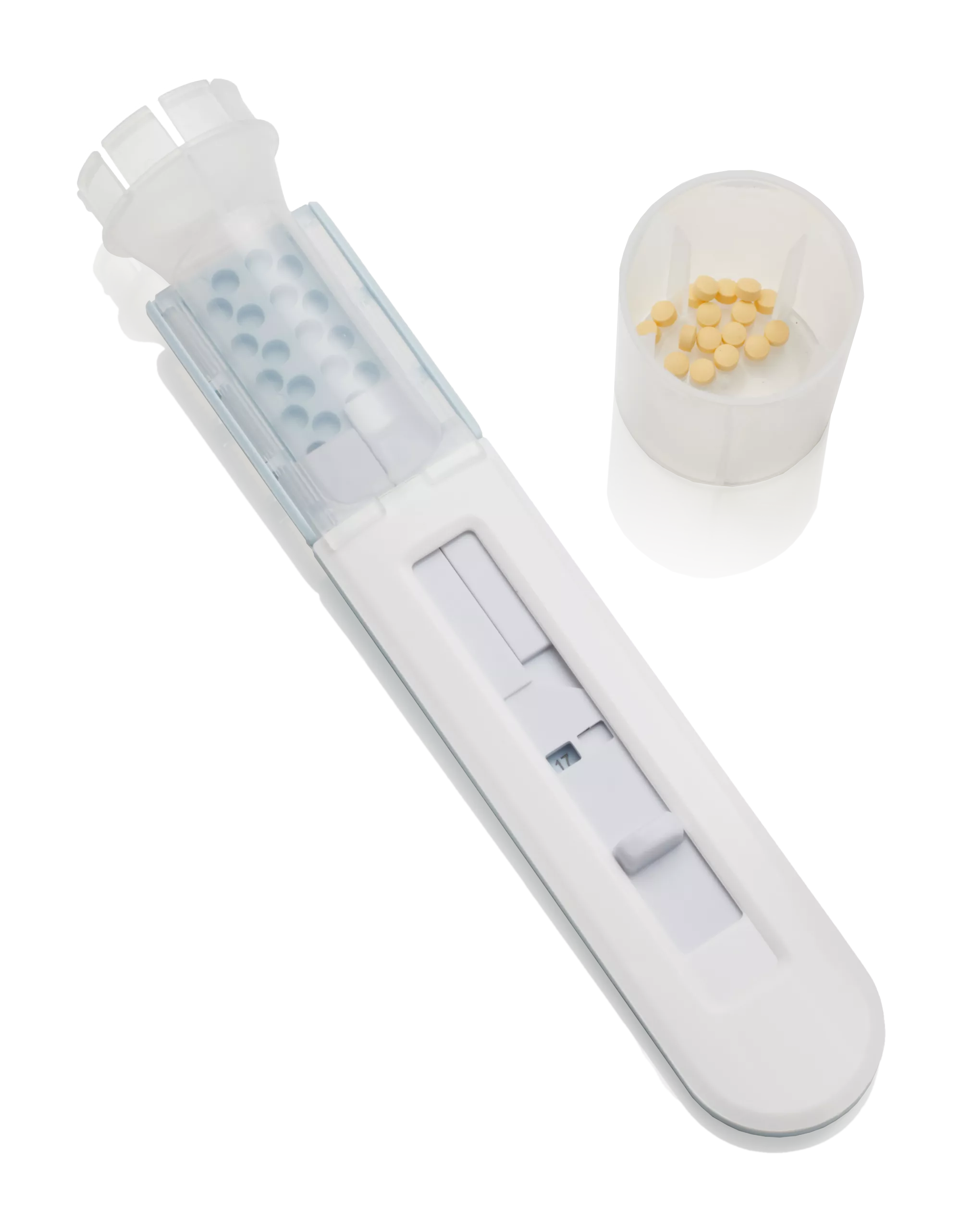 An empty IQ Dose with a yellow mini-tablet in a plastic cup next to it