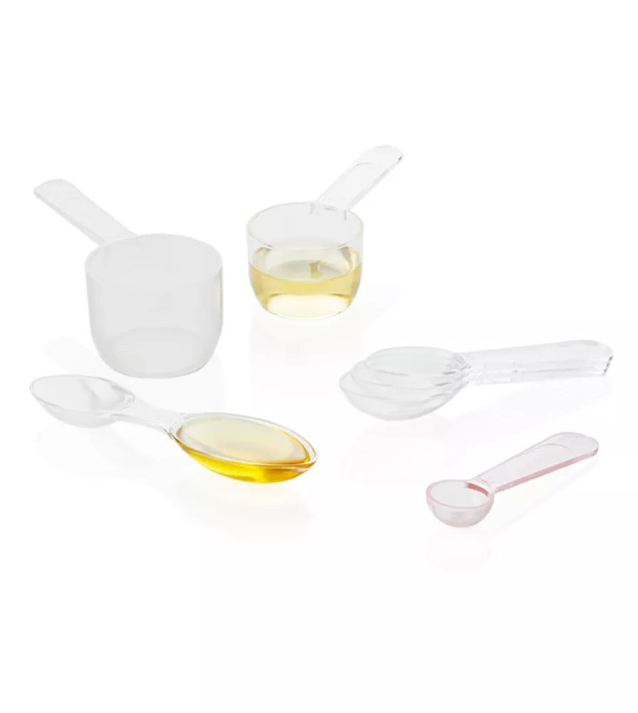 Two transparent cylindrical spoons, one filled with yellow liquid, four stacked transparent oval spoons, one transparent double-dose spoon with one side filled with dark yellow liquid and one transparent semi-spherical spoon.