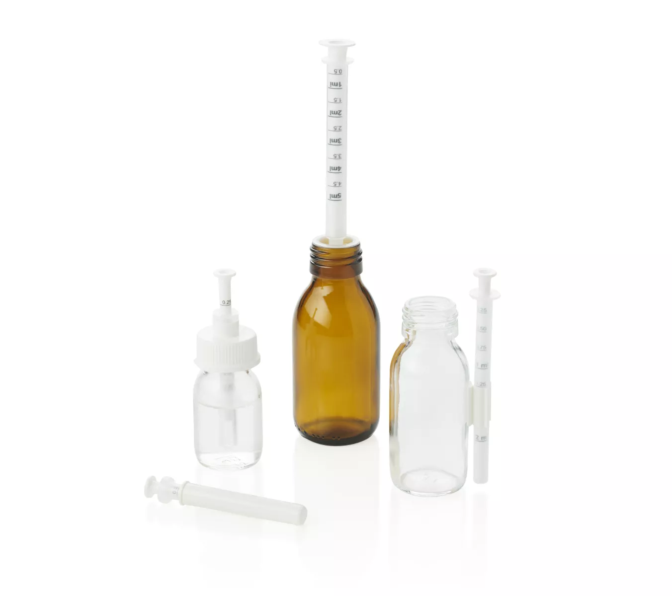 Accessories for dosing pipettes: oral syringe wiper screwed onto a transparent bottle, protective sheath, adaptor mounted on an amber bottle with the pipette and syringe holder glued to a transparent bottle.