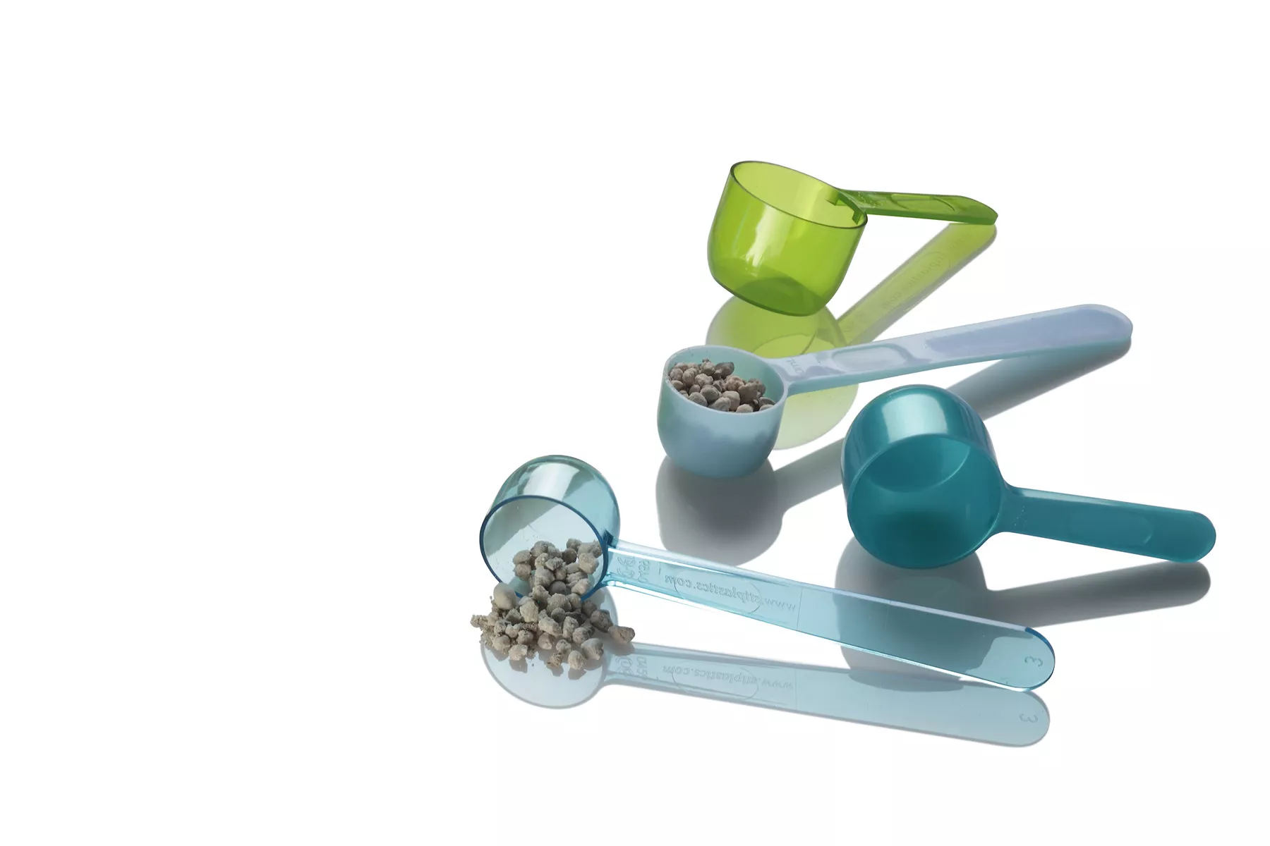 Cuillères cylindriques bleues avec des granulés dans certaines et une cuillère cylindrique verte