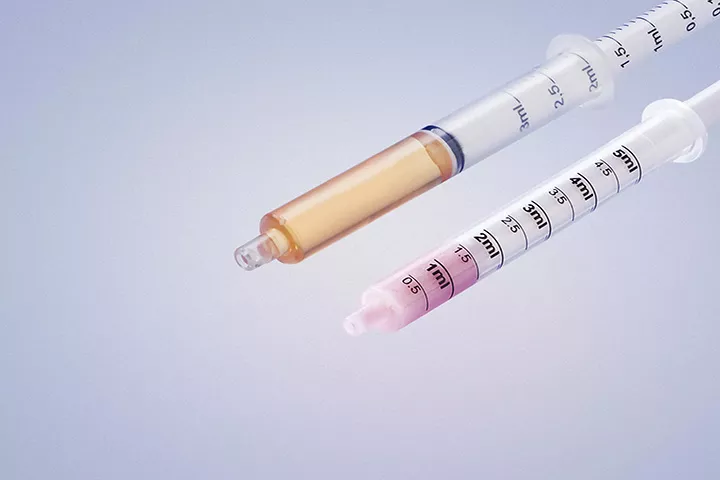A 3ml oral dosing syringe from the Evolution range filled with orange liquid and a 5ml oral dosing syringe from the Advanced range filled with pink liquid.