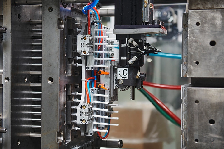 Les pistons des pipettes doseuses viennent d'être injectés et le moule est ouvert. Le robot retire les pistons de leurs cavités.