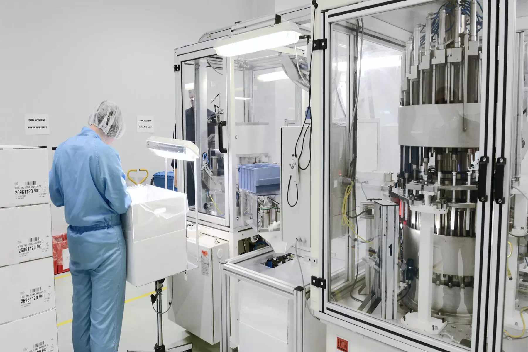Technician carrying out quality control next to a machine assembling plungers with barrels of oral dosing syringes