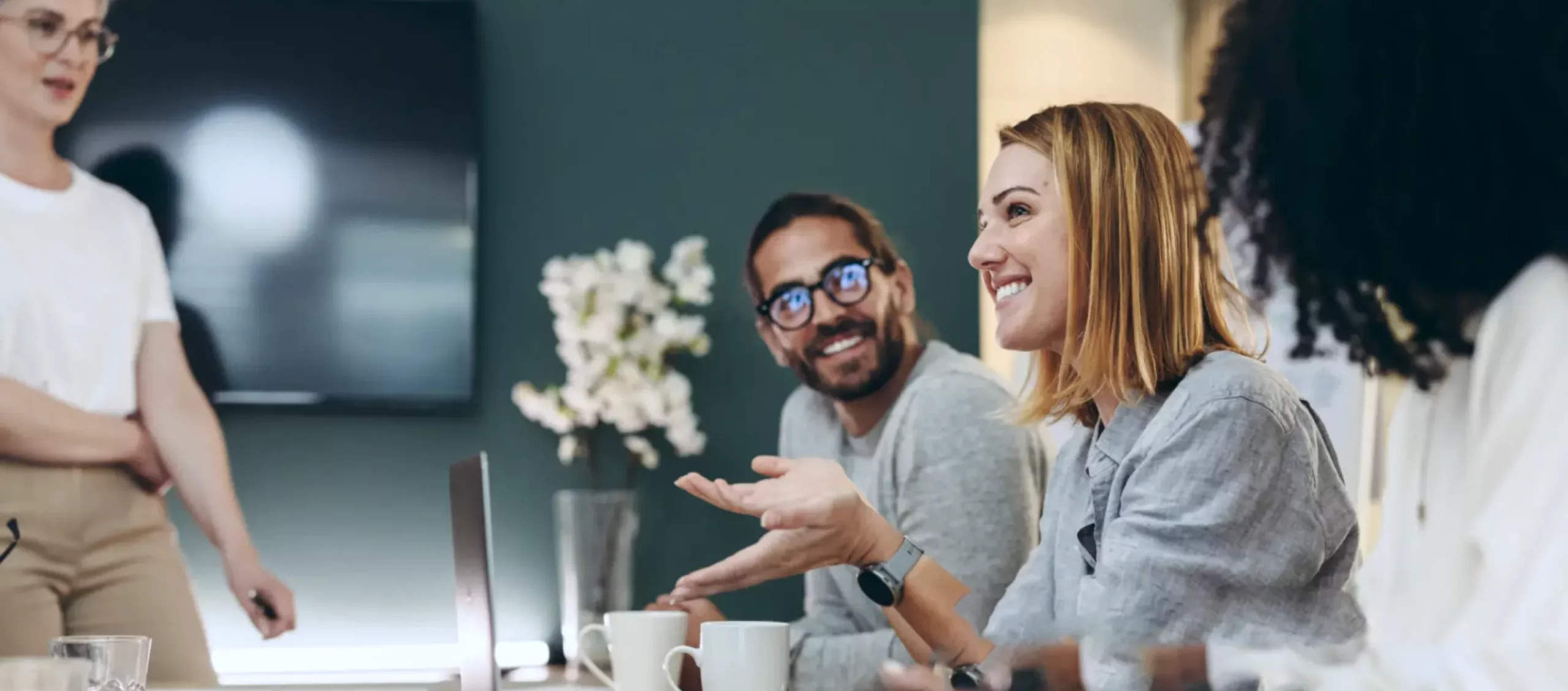 Women and men are smiling while having a conversation around a table